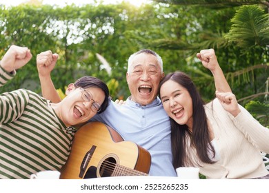 Happy Asian family spending time together, man and woman let their father playing a guitar and singing in backyard garden at home. Mental health care and wellbeing in senior adult. - Powered by Shutterstock