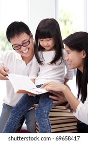 Happy Asian Family Studying Together. Parent Helping Daughter  Reading Book