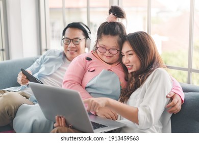Happy asian family with their daughter down syndrome child sitting on sofa  have fun using laptop watch a movie for education , Enjoy relax timing together, Activity happy family lifestyle concept.