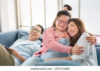 Happy Asian Family With Their Daughter Down Syndrome Child Sitting On Sofa, Girl Hug Her Mother, Enjoy Relax Timing Together, Activity Happy Family Lifestyle Concept.