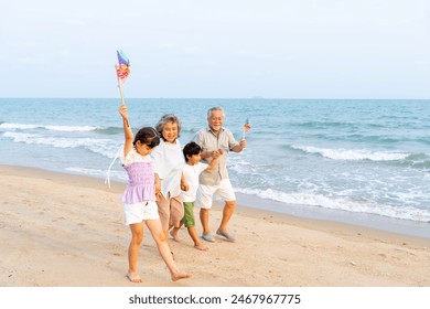 Happy Asian family travel ocean on summer holiday vacation. Grandparents and grandchildren boy and girl enjoy and fun outdoor lifestyle walking and playing together at tropical island beach at sunset. - Powered by Shutterstock