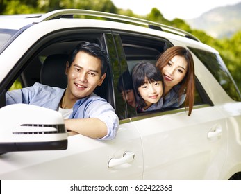 happy asian family traveling by car looking at camera smiling.