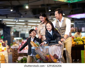 happy asian family with two children shopping in supermarket