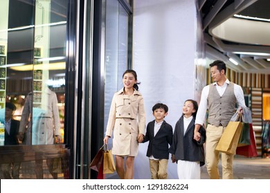 Happy Asian Family With Two Children Walking In Shopping Mall