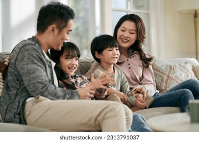 happy asian family with two children sitting on couch at home watching tv together - Powered by Shutterstock