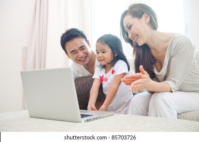 Happy Asian Family Using Laptop With Daugther