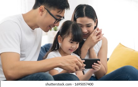 Happy Asian Family Using Phone For Playing Game Or Watching Movies Family And Home Lifestyle Concept