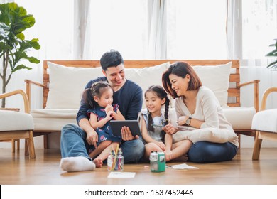 Happy Asian family using tablet, laptop for playing game watching movies, relaxing at home for lifestyle concept - Powered by Shutterstock