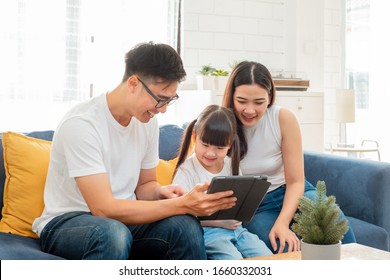 Happy Asian Family Using Tablet, Laptop, Phone For Playing Game Watching Movies, Relaxing At Home For Technology Lifestyle Concept