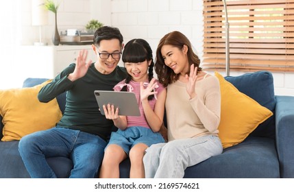 Happy Asian Family Using Tablet Video Call Virtual Meeting Together On Sofa At Home Living Room.