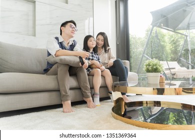 Happy Asian Family Watching Tv Together On Sofa In Living Room. Family And Home Concept