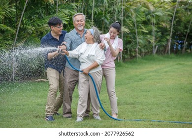 Happy Asian Family Watering The Plants  In The Front Lawn At Home  Spend Time Together Lifestyle In Garden