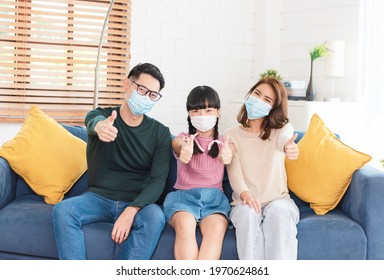 Happy Asian Family Wearing A Mask To Protect Against Viruses At Home Living Room. 