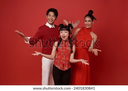 Happy asian family wearing red costume presenting or showing open hand palm with copy space for product isolated on red background. Present product advertising concept.