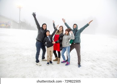 Happy Asian Family In Winter Clothes On The Snow At Ski Resort,Family Enjoyment Winter Holiday Travel Concept