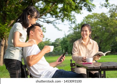 Happy Asian Family,child Girl Or Daughter Enjoy,father Talk,fun Together,parents Drink Coffee Or Tea,smiling Mother Holding Cup Hot And Read A Book Relax In Outdoor Park,family Relationship Concept