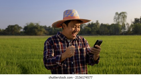 Happy Asian farmer man looking to smartphone display screen with glad wow surprise face at green rice field. - Powered by Shutterstock