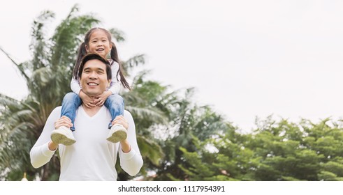 Happy Asian Father And Daughter Playing In The Park. Asian Man Carry Piggyback Little Toddler Girl. Cheerful Family Green Spring Or Summer Father’s Day Together Concept Banner