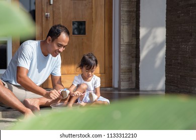 Happy Asian Father With Her Toddler Girl Washing Their Shoes Together At Home. Parent And Kid Working Together