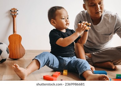 Happy Asian father and little son playing with colorful building blocks and toy cars at home - Shutterstock ID 2369986681
