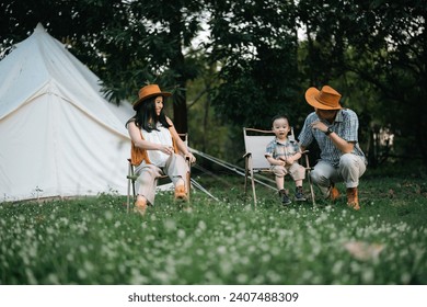 Happy Asian father mother and daughter enjoy camping together at countryside, camping lifestyle with glamping tent - Powered by Shutterstock