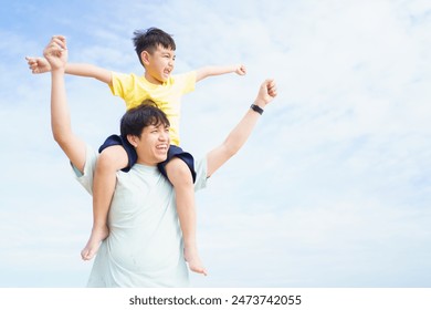 Happy Asian father and son enjoy walking together along the beach, man piggyback his little son while walking at the beach. Family on vacation concept. - Powered by Shutterstock