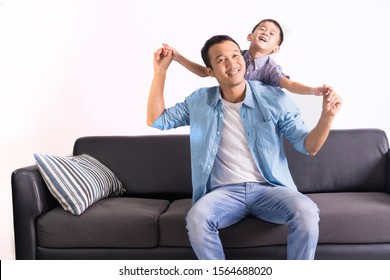 Happy Asian Father And Son Are Sitting On The Couch. Cute Boy With Dad Playing At Home. Happy Family, Father Day