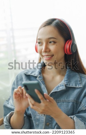 Happy asian female listening to the music on her smartphone.