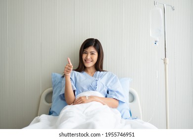 Happy Asian female patient smiling, lies on the bed, and raises thumb up to show confidence in treatment. Concept of believe in treatment And insurance coverage - Powered by Shutterstock