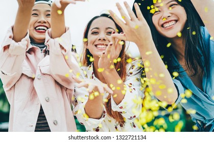 Happy Asian Friends Having Fun Throwing Confetti Outdoor - Young Trendy People Celebrating At Festival Event Outside - Party, Entertainment And Youth Holidays Lifestyle Concept
