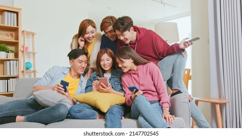 happy asian friends sit sofa watching content on internet talking laughing together on smartphone - Powered by Shutterstock