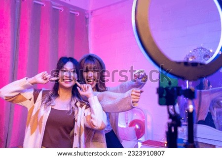 Happy Asian generation z woman friends vlogger influencer content creator enjoy and fun using smartphone online live streaming viral video cover dance on social media application in bedroom at home. [[stock_photo]] © 