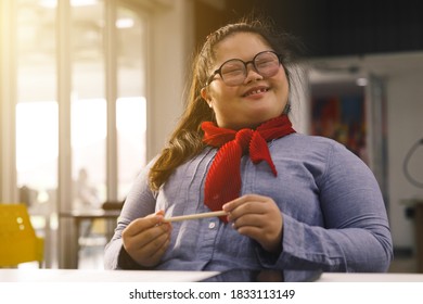 Happy Asian girl with Down's syndrome sit in classroom. Concept disabled kid learning.