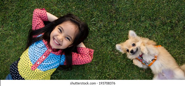Happy Asian girl with her doggy portrait lying on lawn