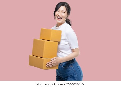 Happy Asian Girl Holding Package Parcel Boxs Isolated On Pink Screen Background. Delivery Courier And Shipping Service Concept.