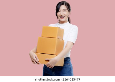 Happy Asian Girl Holding Package Parcel Boxs Isolated On Pink Screen Background. Delivery Courier And Shipping Service Concept.