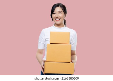 Happy Asian Girl Holding Package Parcel Boxs Isolated On Pink Screen Background. Delivery Courier And Shipping Service Concept.