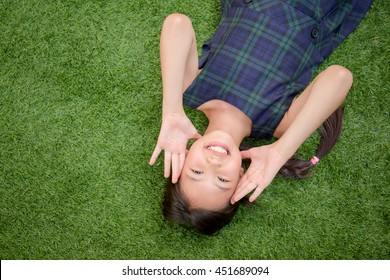 Happy Asian Girl Laying Down On The Green Grass With Copy Space