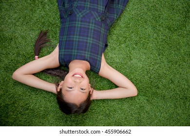 Happy Asian Girl Laying Down On The Green Grass With Copy Space