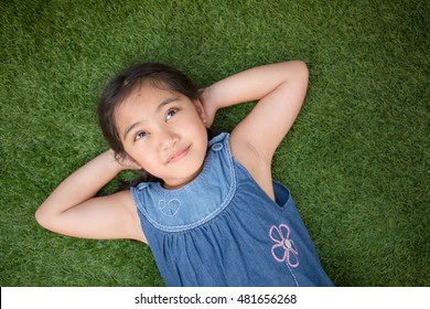 Happy Asian Girl Laying Down On The Green Grass