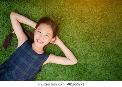 Happy Asian Girl Laying Down On The Green Grass