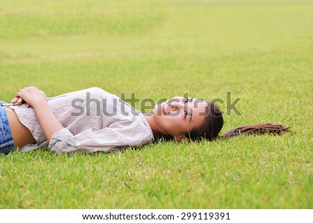 Happy Asian girl lying in the grass
