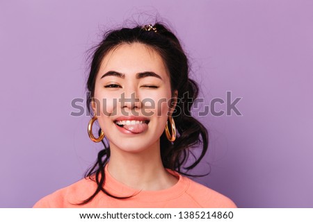 Happy asian girl making funny faces. Front view of trendy japanese young woman in earrings.