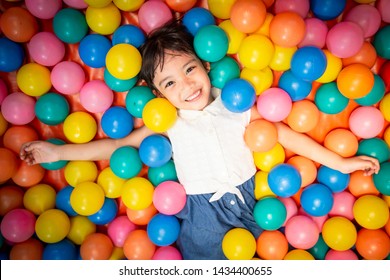 Happy asian girl playing in colorful balls pool