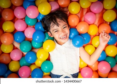 Happy asian girl playing in colorful balls pool