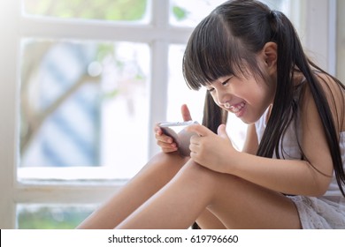 Happy Asian Girl Playing Game On Mobile Phone