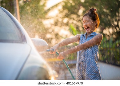 Happy Asian Girl Washing Car On Water Splashing And Sunlight At Home