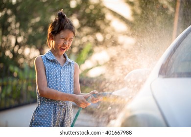 Happy Asian girl washing car on water splashing and sunlight at home - Powered by Shutterstock