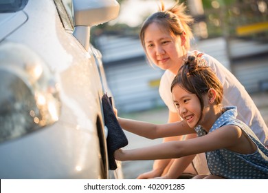 Happy Asian Girl Washing Car With Her Mother At Home