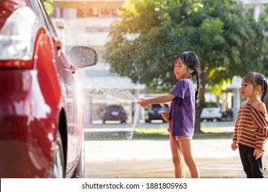 Happy Asian Girl Washing Red Car On Water Splashing And Sunlight At Home.